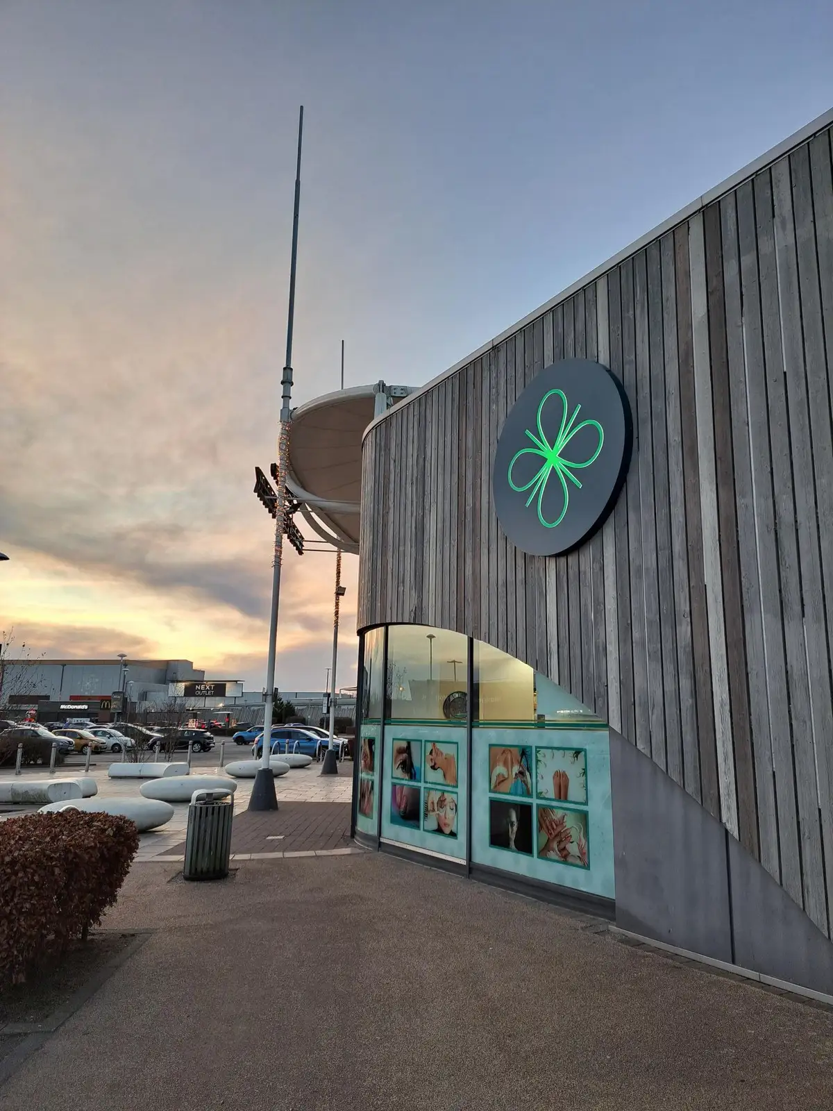 Modern building with a green logo, large windows, and a cloudy sky in the background.