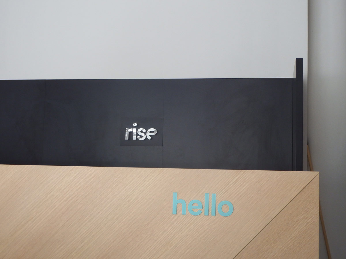 A black wall with "rise" and a wooden panel with "hello" in blue letters.