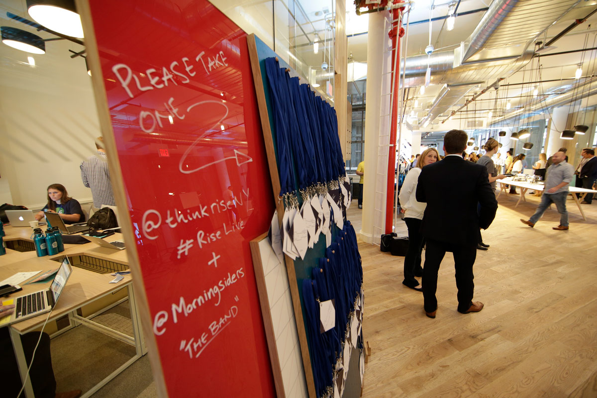 People are gathered in a modern office space with a red board and blue bags displayed.