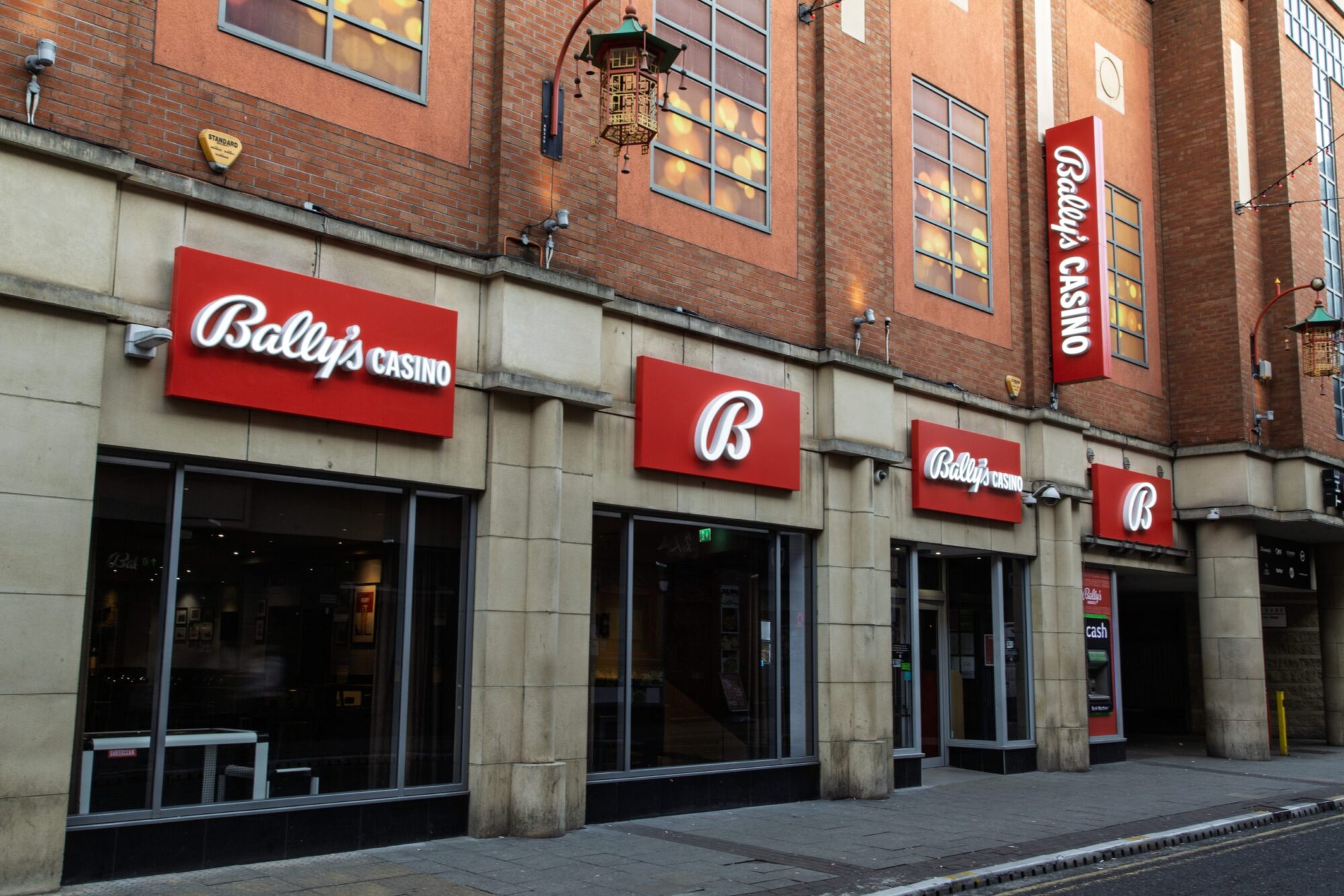 Exterior of Bally's Casino with red signs and large windows on a brick building.