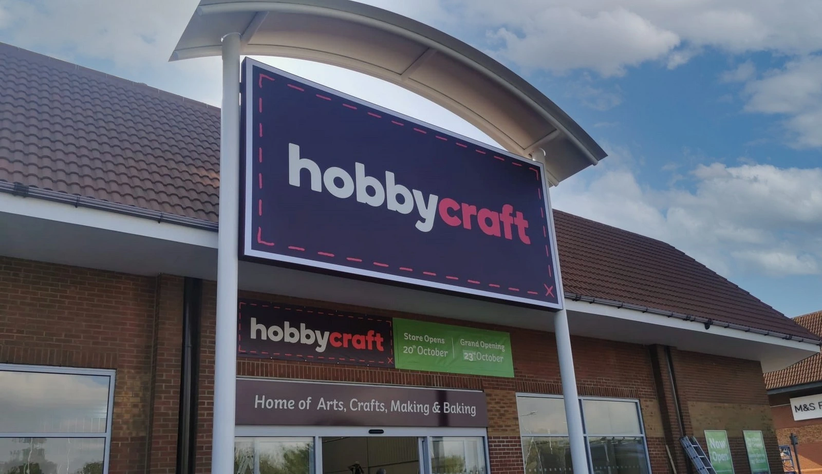 Hobbycraft store entrance with large sign and blue sky in the background.