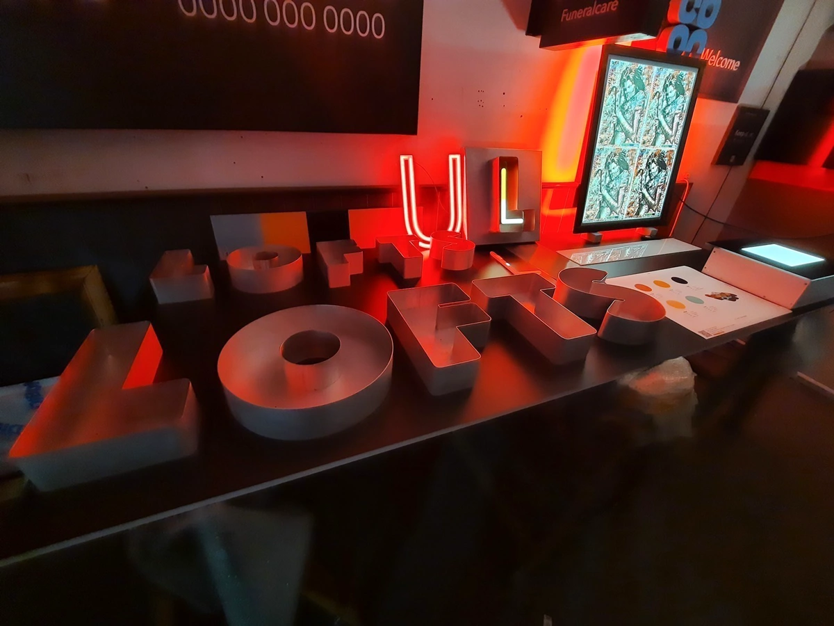 Large 3D letters spelling "LOFTS" on a table with red lighting and a screen.