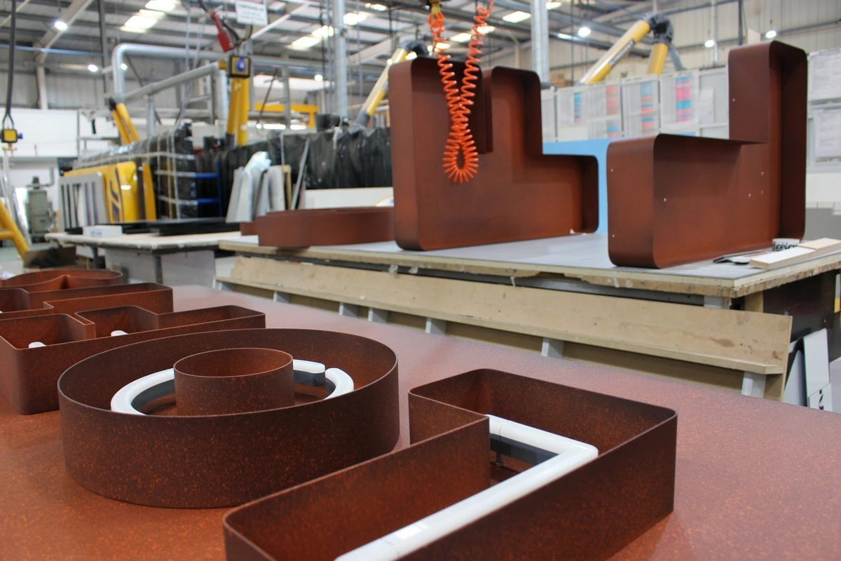 Rust-colored metal structures with white interiors on a workshop table in an industrial setting.