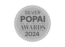Silver POPAI UK & Ireland Awards 2024 badge with embossed text, circular design, and serrated edges.