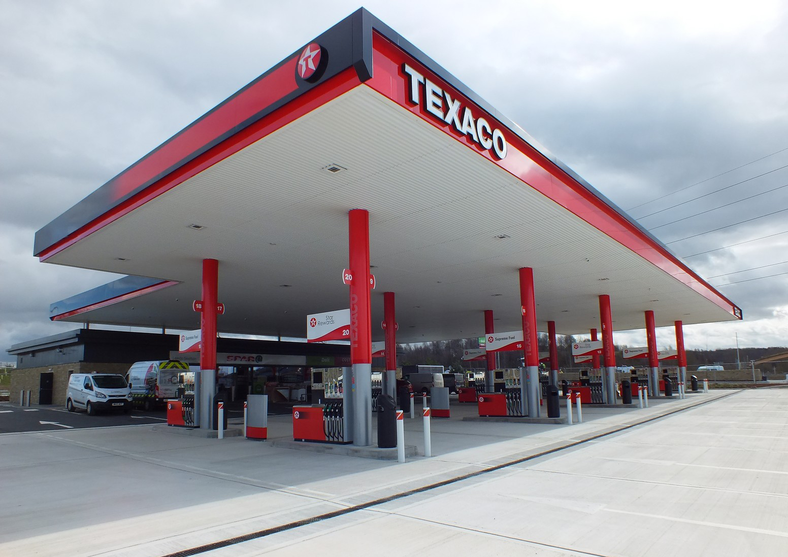A Texaco gas station with multiple fuel pumps and a cloudy sky in the background.