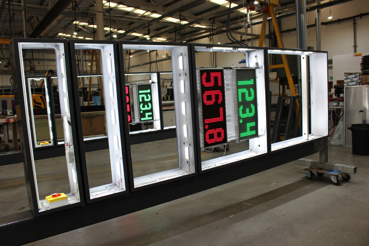Large digital display panels with numbers are being assembled in a spacious industrial workshop.